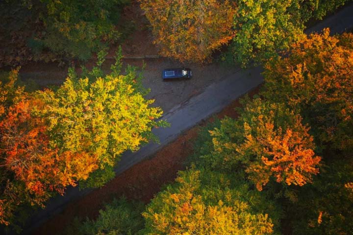 An aerial shot of a campervan driving through trees