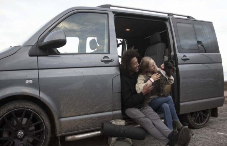 Two people with a dog sitting in a campervan