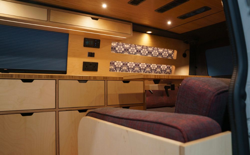 Wooden kitchen in campervan with blue blinds, william morris blue tiles and burgundy upholstery 