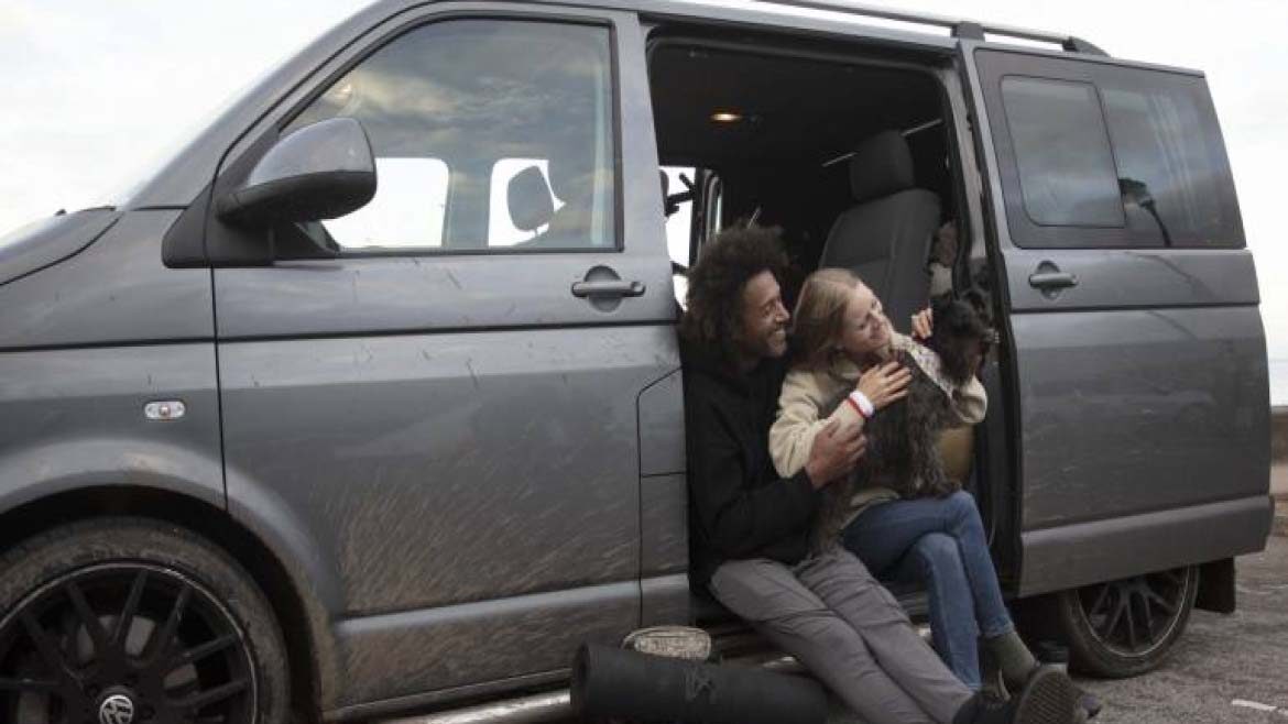 Two people with a dog sitting in a campervan