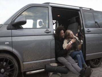 Two people with a dog sitting in a campervan