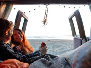 Two people lauging in a campervan under a blanket
